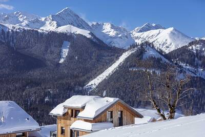 Detached holiday home in the snow at Almdorf Hohentauern and the mountains in the background