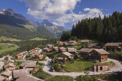 Aerial view of chalets at Alps Resorts Alpendorf Dachstein West, with mountains behind