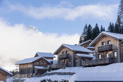 Chalets on a mountain slope covered in snow at Alps Resorts Alpendorf Dachstein West