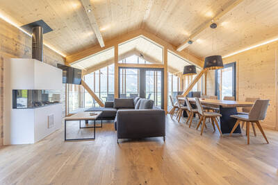 Living room with fireplace, sitting area and dining table of a chalet at  Bergresort Hauser Kaibling