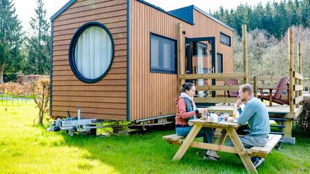 A couple at a picnic table at a tiny house at Landal Nature Parc Saint Hubert