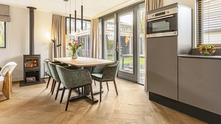 Dining table, kitchen and wood stove of a holiday home at Landal Residence Berger Duinen