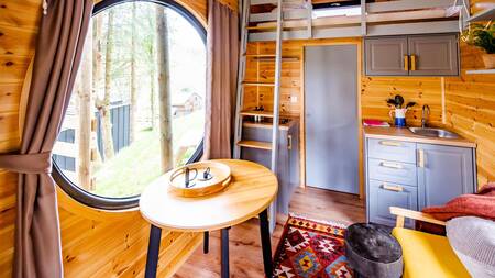 Dining table, kitchen and bed in a tiny house at Nature Parc Saint Hubert