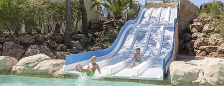 Children slide down the wide slide in the outdoor pool of holiday park RCN Domaine de la Noguière